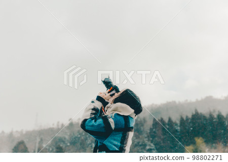 一位年輕女子在雪地裡拿著相機的照片 98802271