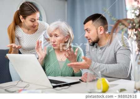Young couple helping elderly woman use laptop 98802618