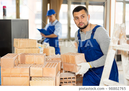 Repairman carrying bricks in construction site Repairman carrying bricks in construction site 98802765