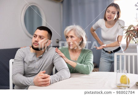 Quarrel between husband and wife, senior mother comforting adult son 98802784