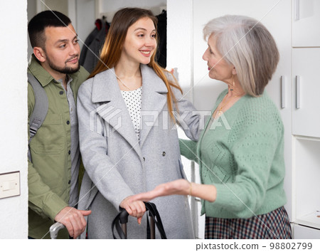 Elderly woman meeting young couple at doorway Elderly woman meeting young couple at doorway 98802799
