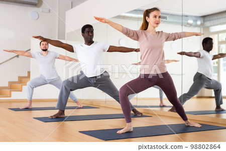 People exercising warrior two asana in gym 98802864