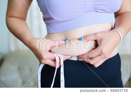 Fat woman measuring , fat woman fat belly chubby paunchy sport recreation health care lose belly fat concept, woman holding excessive belly with measure tape Fat woman measuring , fat woman fat belly chubby paunchy sport recreation health care lose belly fat concept, woman holding excessive belly with measure tape 98803730