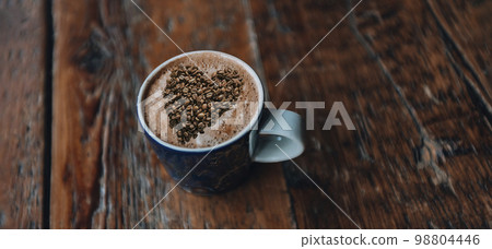 Coffee. Creative Love of Coffee Concept Image. Coffee cup with cappuccino and coffee beans heart shaped art at cafe table 98804446