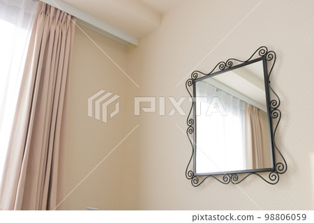 A stylish mirror on the wall of a white room A stylish mirror on the wall of a white room 98806059