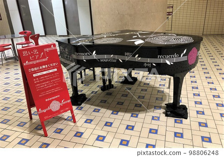 一個紅色的標誌，上面寫著 Kanazawa Station Memories Piano 和一架黑色三角鋼琴 98806248