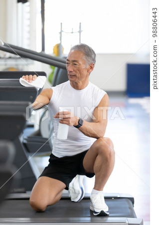 A well-mannered senior man who cleans and disinfects the used training machine A well-mannered senior man who cleans and disinfects the used training machine 98806443