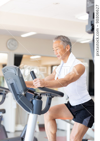 Senior man riding an exercise bike 98806627