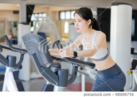 Young woman riding an exercise bike 98806756