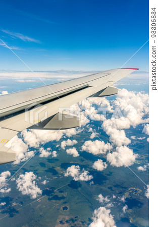 View from the airplane window at a beautiful cloudy sky and the airplane wing 98806884