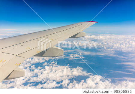 View from the airplane window at a beautiful cloudy sky and the airplane wing View from the airplane window at a beautiful cloudy sky and the airplane wing 98806885