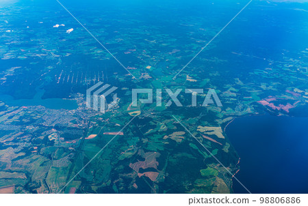 Aerial view from airplane window above green ground. View from the airplane window with beautiful clouds at sunrise Aerial view from airplane window above green ground. View from the airplane window with beautiful clouds at sunrise 98806886