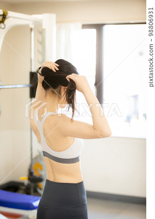 Young woman tying her hair up before exercising Young woman tying her hair up before exercising 98806931