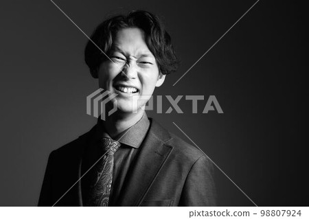 穿著單色西裝的皺著眉頭的年輕人 98807924