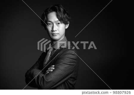 年輕商人一邊折疊雙臂一邊看單色圖像 98807926