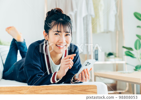 Young woman looking at her smartphone in the living room Young woman looking at her smartphone in the living room 98808053