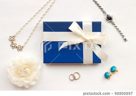 Present image of a blue gift box with a white ribbon and accessories Present image of a blue gift box with a white ribbon and accessories 98808897
