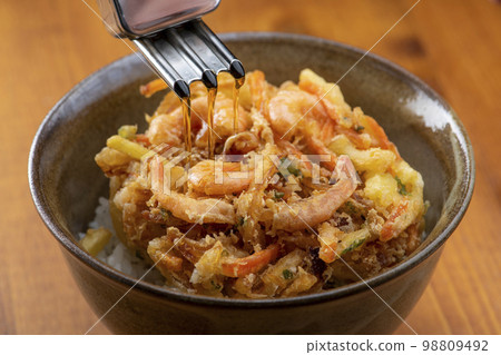 Pour the tempura sauce over the kakiage rice bowl 98809492