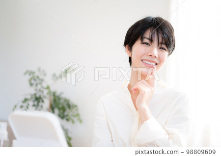 A woman looking at her teeth in the mirror looking at the camera 98809609