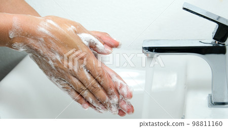 Hands of woman wash their hands in a sink with foam to wash the skin and water flows through the hands. Concept of health, cleaning and preventing germs and coronavirus from contacting hands 98811160