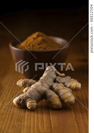 秋天薑黃根莖和薑黃粉末在木桌上 98812504