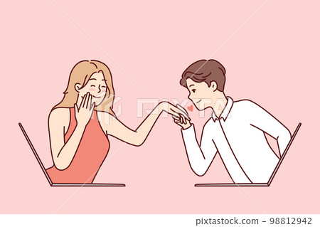 Determined guy kisses hand of embarrassed girl looking out of laptop screen Determined guy kisses hand of embarrassed girl looking out of laptop screen 98812942
