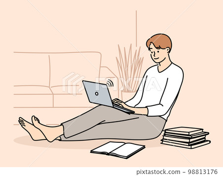 Man student sits on floor with laptop on knees near books receives distance education Man student sits on floor with laptop on knees near books receives distance education 98813176