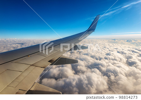 Commercial Airplane Flying over the Clouds - Looking through the Plane Window Commercial Airplane Flying over the Clouds - Looking through the Plane Window 98814273