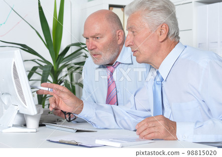 Senior businessmen sitting at desk and working Senior businessmen sitting at desk and working 98815020
