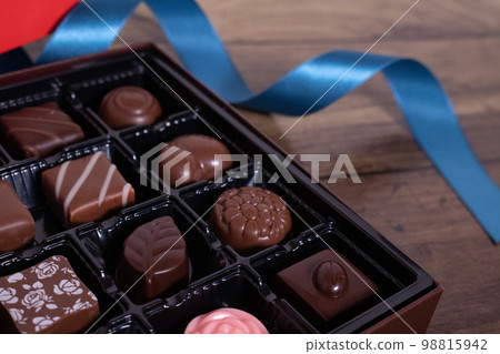 Assorted chocolates and blue ribbon Assorted chocolates and blue ribbon 98815942