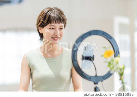 A young woman in a dress who streams videos in an open room 98816883
