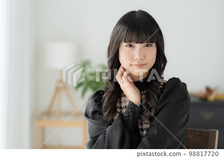 Z 世代女孩坐在客廳的椅子上看著鏡頭的肖像 98817720