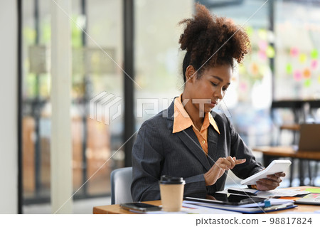 Concentrated female accountant comparing corporate income for previous year with current one at her workstation Concentrated female accountant comparing corporate income for previous year with current one at her workstation 98817824