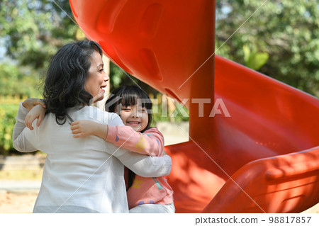 Adorable little grandchild playing with her grandmother on outdoor playground. Family and love concept 98817857