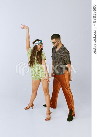 Attraction. Pretty young girl and handsome man in stylish retro clothes dancing disco dance isolated over grey studio background. American culture, hobby Attraction. Pretty young girl and handsome man in stylish retro clothes dancing disco dance isolated over grey studio background. American culture, hobby 98819600