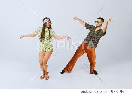 Pretty young girl and handsome man in stylish retro clothes dancing disco dance isolated over grey studio background. American culture, hobby Pretty young girl and handsome man in stylish retro clothes dancing disco dance isolated over grey studio background. American culture, hobby 98819601