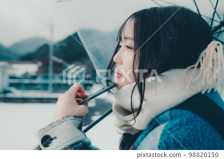 Photo of a young woman holding a smartphone in the snow 98820150