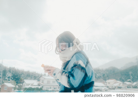 Photo of a young woman having a warm drink in the snow 98820906