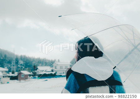 Photo of a young woman holding an umbrella in the snow 98822150