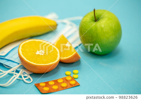 Fruits and pills on a blue background, disease prevention concept. Fruits and pills on a blue background, disease prevention concept. 98823626
