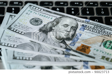 Close up, dollar bills on laptop, money making concept. Close up, dollar bills on laptop, money making concept. 98823713