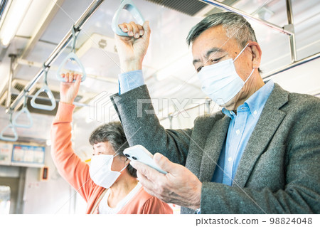 Senior men and women who are caught by a strap and use a smartphone 98824048