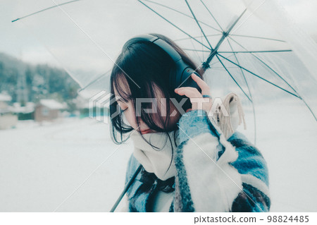 一位年輕女子在雪地裡聽音樂的照片 一位年輕女子在雪地裡聽音樂的照片 98824485