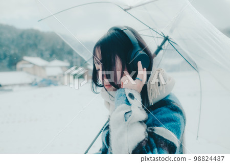 一位年輕女子在雪地裡聽音樂的照片 一位年輕女子在雪地裡聽音樂的照片 98824487