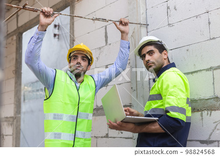 Professional construction engineer team, Two man engineer wear uniform holding laptop Professional construction engineer team, Two man engineer wear uniform holding laptop 98824568