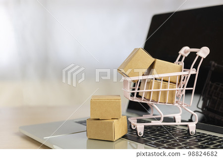 shopping online and logistic concept. paper box in small shopping cart on computer laptop. shopping online and logistic concept. paper box in small shopping cart on computer laptop. 98824682
