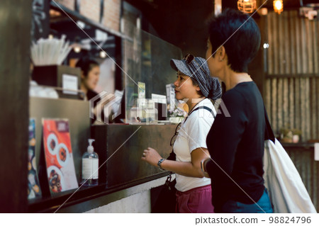 Two women friends placing an order to take out in a coffee shop. Two women friends placing an order to take out in a coffee shop. 98824796