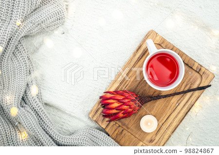 A cup of red tea and a flower on a wooden tray in bed, top view. A cup of red tea and a flower on a wooden tray in bed, top view. 98824867