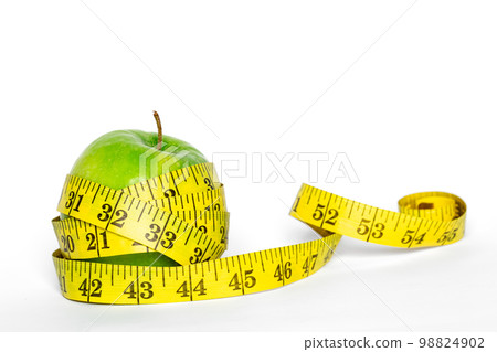 Green apple and meter on a white background isolated. Green apple and meter on a white background isolated. 98824902