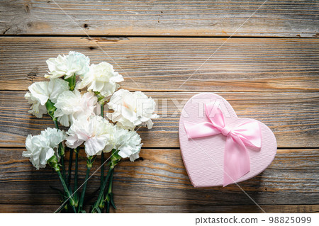 Bouquet of flowers and heart shaped gift box on wooden background, flat lay. Bouquet of flowers and heart shaped gift box on wooden background, flat lay. 98825099